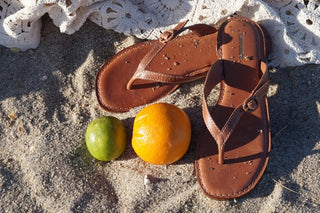 Chinelos na areia e frutas