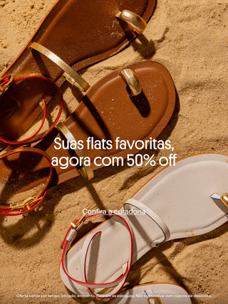 Sandálias rasteiras brancas e marrons com detalhes metálicos dourados dispostas sobre areia, com texto promocional ao centro: “Suas flats favoritas, agora com 50% off” e chamada para ação “Confira a curadoria”.