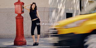 “Mulher vestindo conjunto preto encostada em um hidrante vermelho na calçada. Texto sobreposto: ‘Antecipe o inverno’, ‘50% off em todo o site’ e botão ‘Comprar agora’.”