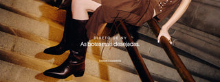 Banner com modelo sentada em escada usando botas de couro preto de cano médio e salto baixo. Sobreposição de texto: “Direto de NY. As botas mais desejadas.” e chamada “Explore a curadoria”.