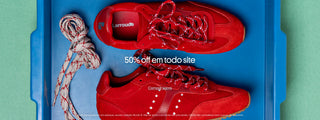 Banner promocional com par de tênis vermelhos Larroudé dentro de uma caixa azul, com cadarços extras ao lado. Texto sobreposto: “50% off em todo site” e “Compre agora”. Rodapé informa: válido para produtos em estoque, exceto coleção Nicoló B.; não se aplica a pré-venda; oferta não cumulativa com cupons.