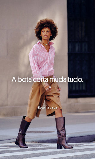 Bota cano longo preta com look casual de saia midi caramelo e camisa listrada rosa